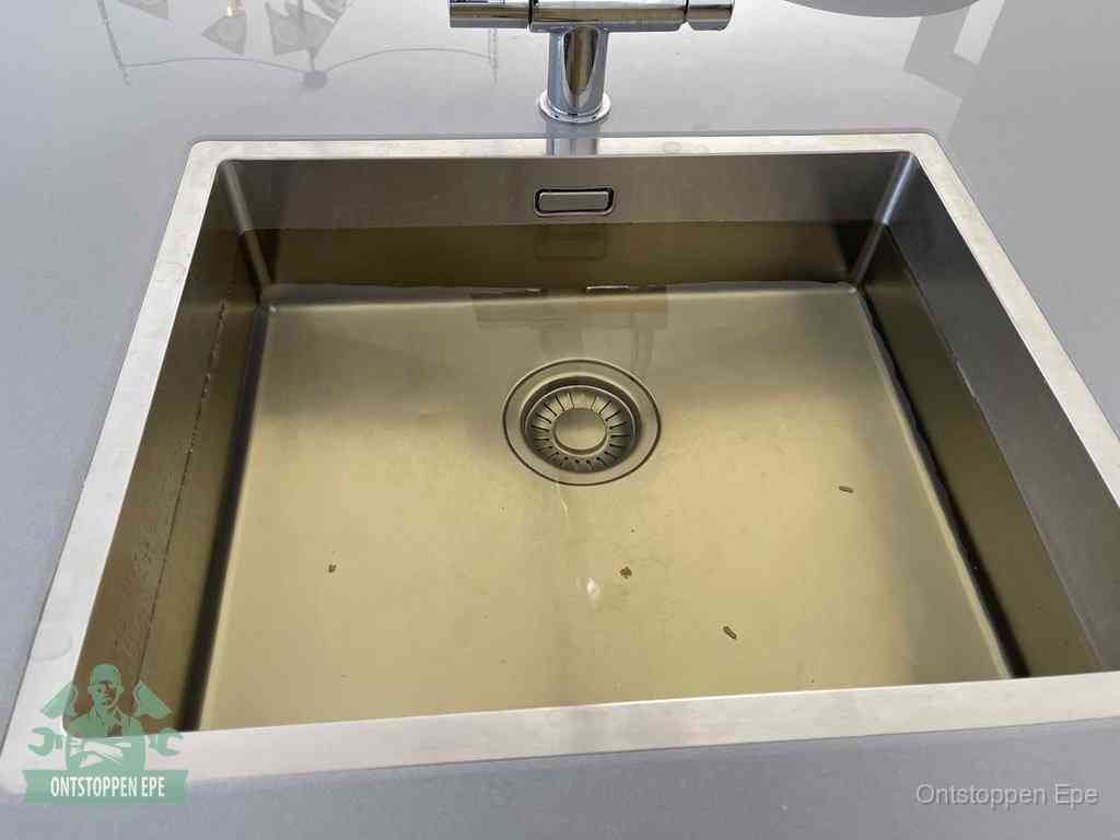 Stilstaand water in een rvs spoelbak dat niet wegloopt, een duidelijk signaal van een gootsteenverstopping in Epe