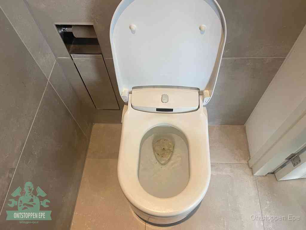 Een wit hangtoilet waarin een prop wc-papier op het water blijft drijven, een duidelijk signaal van een verstopte wc in Epe
