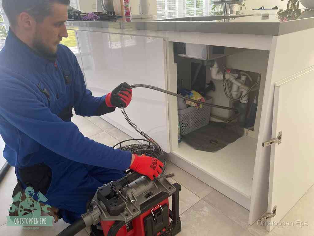 Een monteur reinigt de keukenafvoer grondig met een veermachine om terugkerende gootsteenverstoppingen te voorkomen in Epe